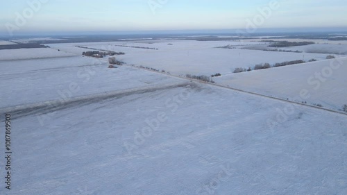 Aerial looking down onto vast snow covered flat prairie farmland with gravel roads
