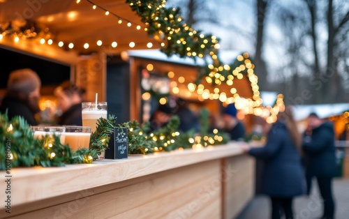 Two drinks on a wooden table at a festive market with Christmas lights in the...