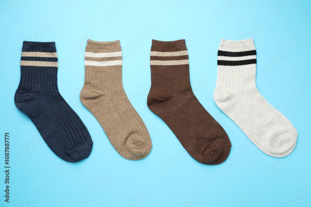 Different comfortable socks on light blue background, flat lay