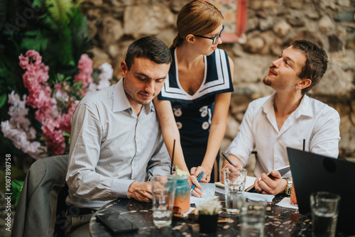 A group of professionals engaged in a collaborative discussion outdoors at a cozy cafe  highlighting teamwork and creativity in a relaxed environment.
