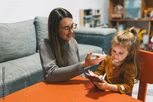 A warm and family-oriented home setting is displayed, where interactive digital learning takes place, facilitated by a caring adult assisting a curious child. photo