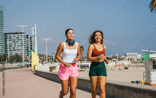 Canvas Print Two young women running along the beach in barcelona
