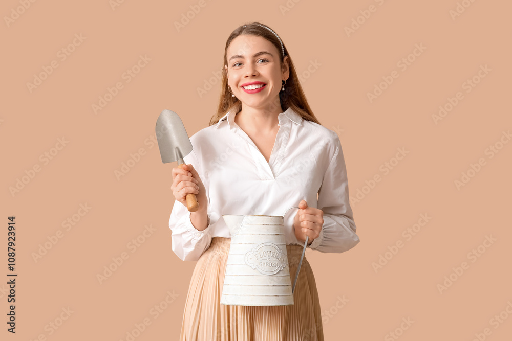 Beautiful young woman with watering can and gardening shovel on brown background Beautiful young woman with watering can and gardening shovel on brown background