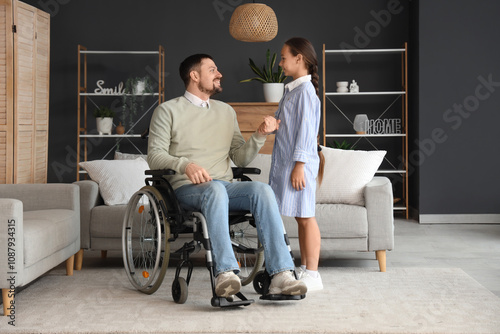 Father in wheelchair holdin...