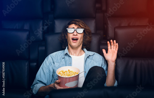 Entertainment concept. Young guy in 3D glasses being scared in movie theater photo