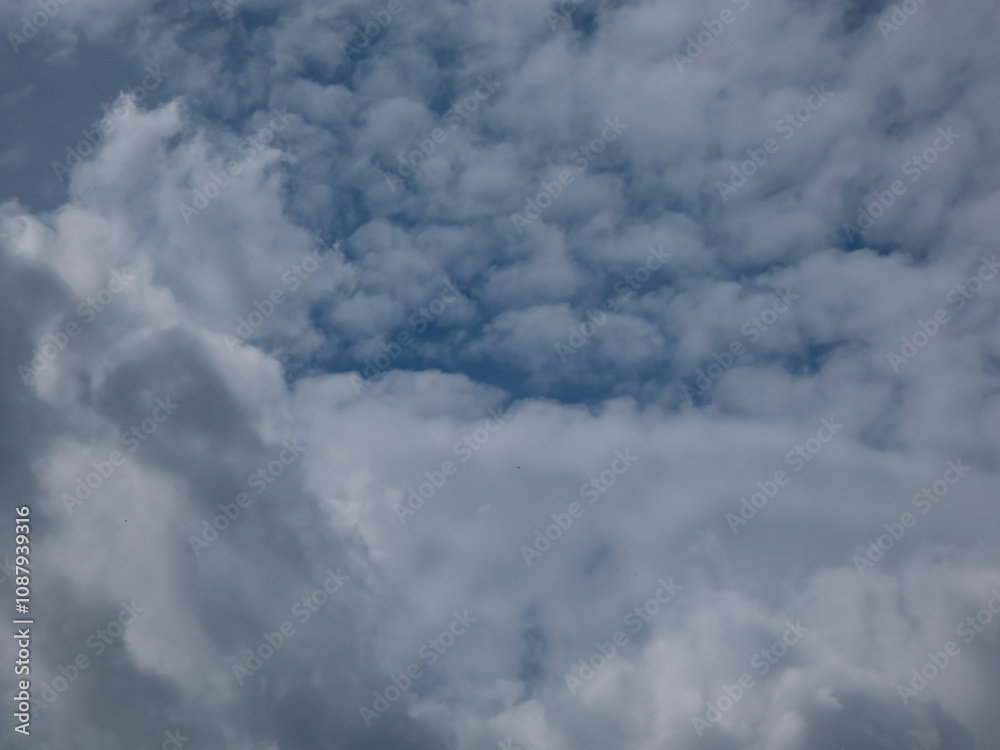 Fototapeta premium View of blue sky with fluffy white clouds in a sunny day. Dark sky sunlit with beautiful white clouds