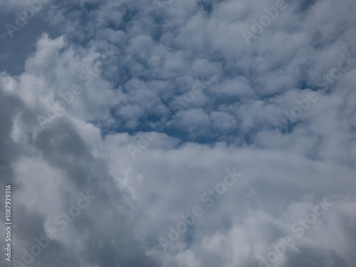 View of blue sky with fluffy white clouds in a sunny day. Dark sky sunlit with beautiful white clouds