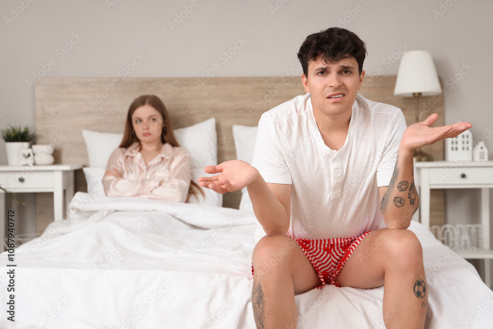 Fototapeta premium Upset young man sitting in bedroom. Sexual problems concept