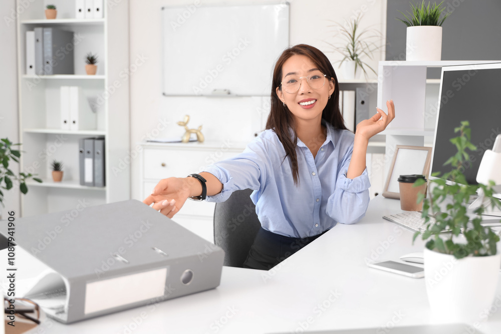 Asian businesswoman working with folder at desk in office Asian businesswoman working with folder at desk in office