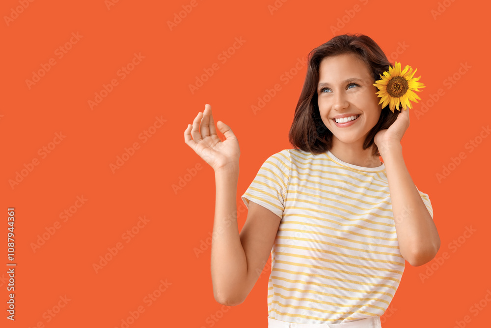 Beautiful young happy woman with sunflower in her hair on orange background Beautiful young happy woman with sunflower in her hair on orange background
