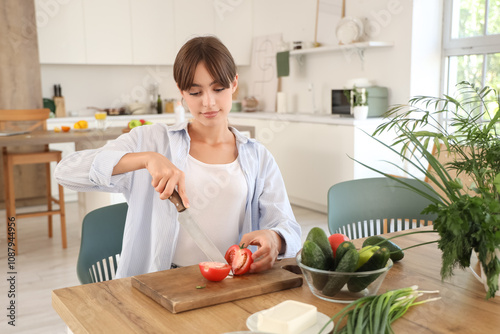 Young woman cutting tomato ...