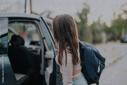 A young girl exits a car wearing a backpack, ready for school on a bright morning. The moment captures the everyday routine of a school drop-off and the anticipation of a new day. photo