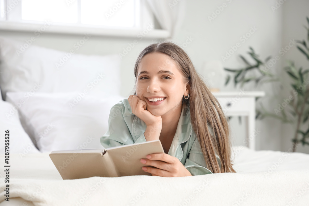 Young pretty woman in pajamas reading book on bed at home Young pretty woman in pajamas reading book on bed at home