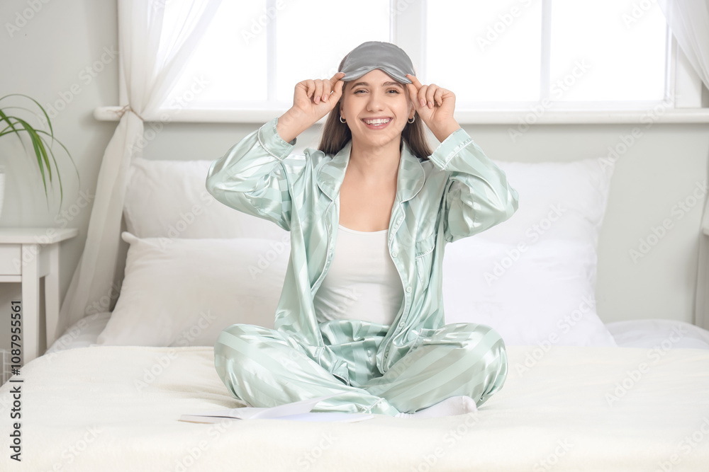 Young pretty woman in pajamas sitting on bed at home Young pretty woman in pajamas sitting on bed at home