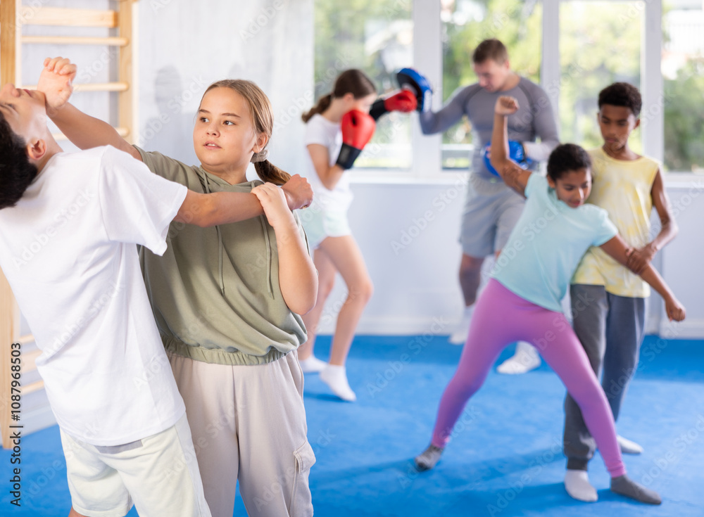Naklejka premium Preteen children pairs learning strength self-defense in the gym
