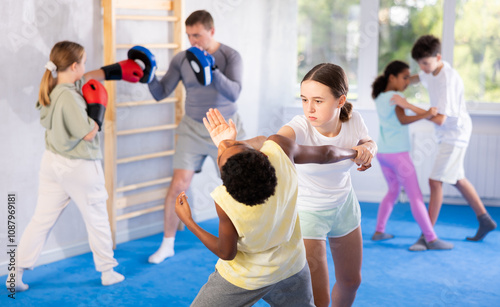 Girls and boys learns to do power grip with trainer during a self-defense lesson in the gym photo