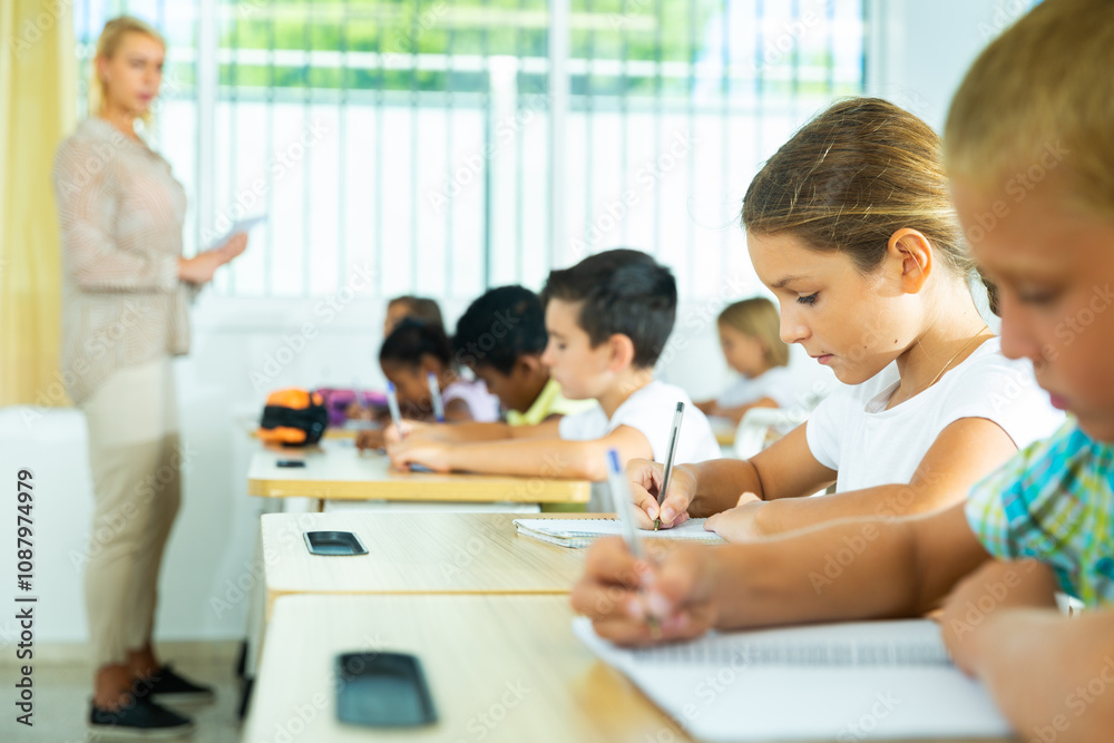 Group of focused pupils sitting at classroom working at class with teacher Group of focused pupils sitting at classroom working at class with teacher
