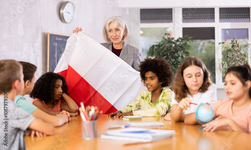 listening to teacher s story about Poland, child examines this country on globe photo