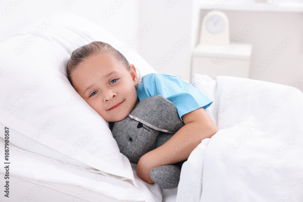 Cute little girl with toy bunny on bed in hospital Cute little girl with toy bunny on bed in hospital