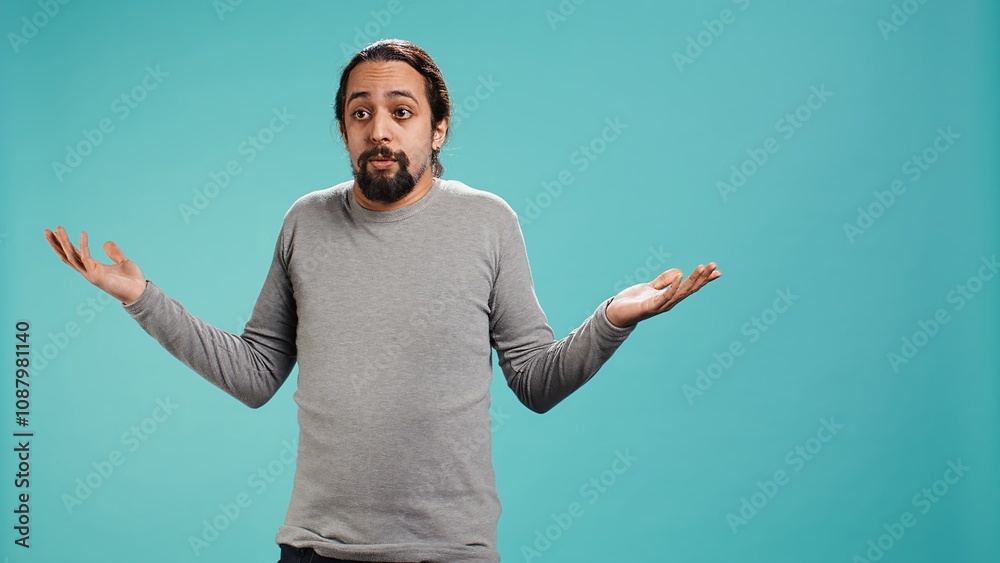 Naklejka premium Man shrugging shoulders, unable to provide answer, having detached apathy facial expression. Apathetic person doing hand gesturing showing lack of knowledge, studio background, camera B