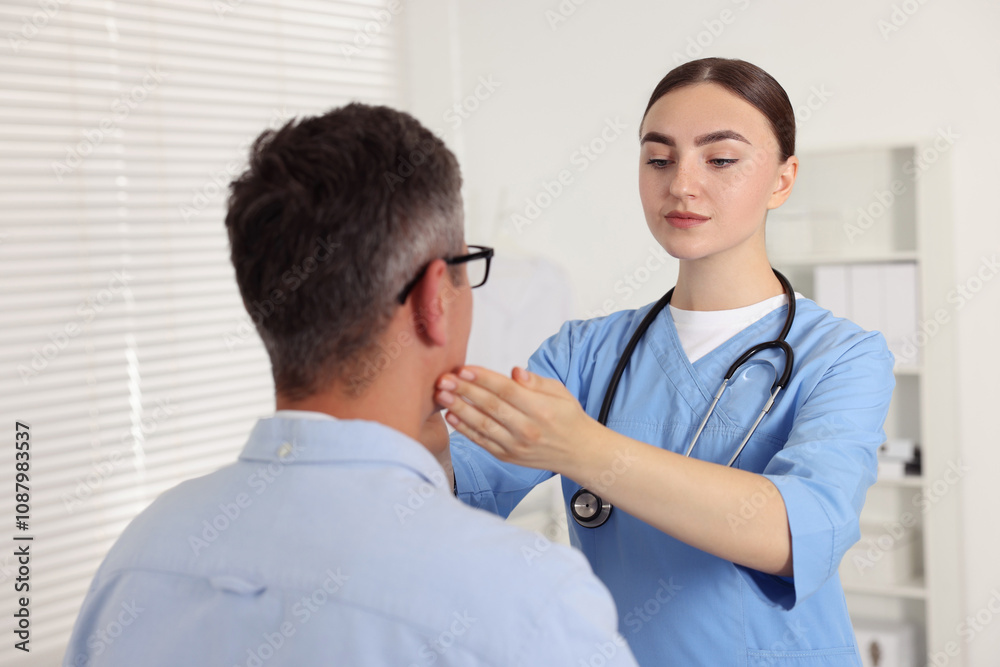 Doctor examining man's throat in clinic during appointment Doctor examining man's throat in clinic during appointment