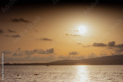 Golden Sunset over Calm Sea. Beautiful sunset scene over the water, golden hour light, peaceful ocean. Warm colors, tranquil landscape, summer vacation, travel photography.