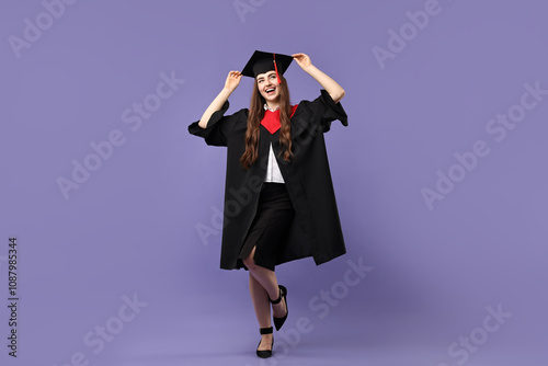 Happy student after graduation on violet background photo