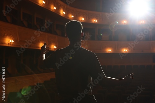 Professional actor rehearsing on stage in theatre, back view photo