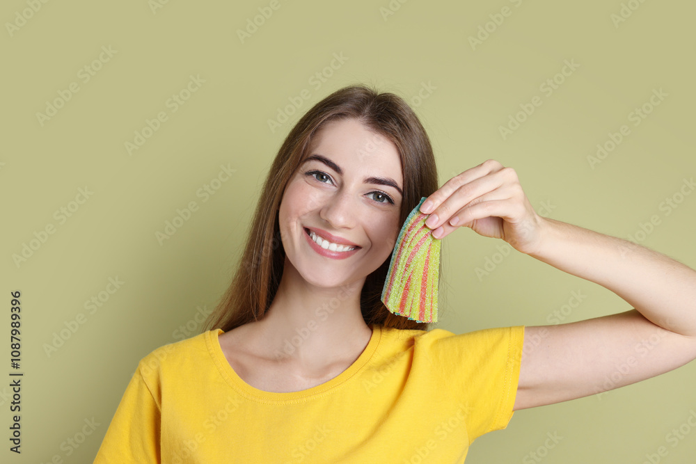 Happy young woman with tasty rainbow sour belts on olive background Happy young woman with tasty rainbow sour belts on olive background