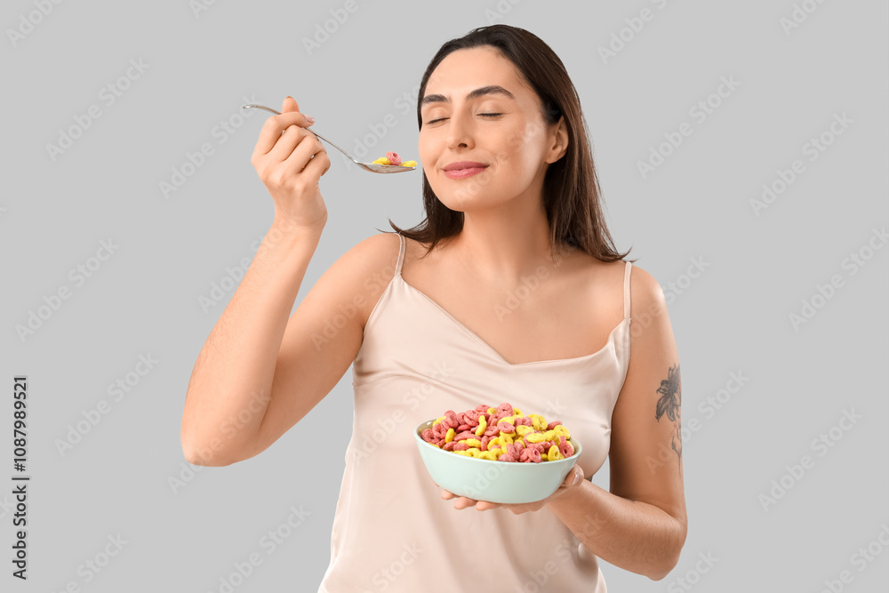 Young woman in pajamas eating cereal rings on light background Young woman in pajamas eating cereal rings on light background
