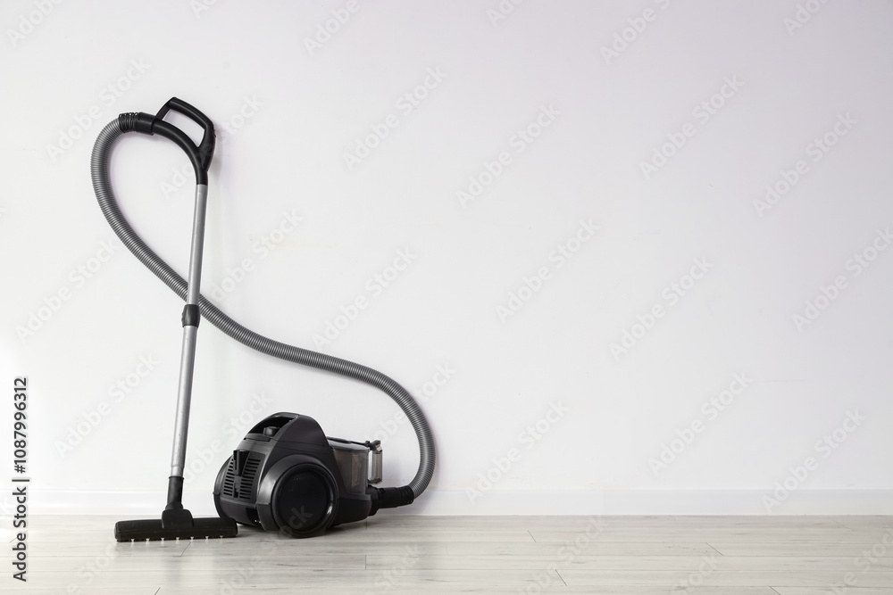 Modern vacuum cleaner near light wall in room Modern vacuum cleaner near light wall in room