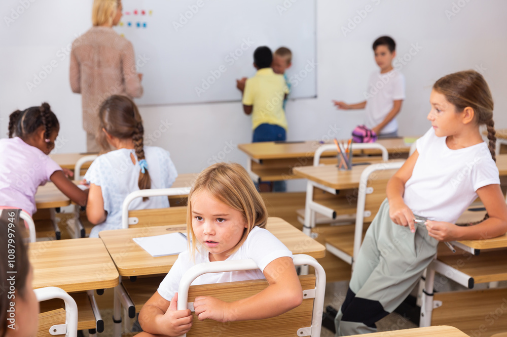 Positive primary school students are talking about homework at the desk Positive primary school students are talking about homework at the desk