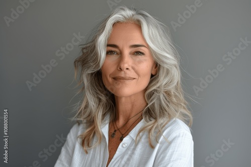 Stylish senior woman with grey hair smiling in white shirt portrait