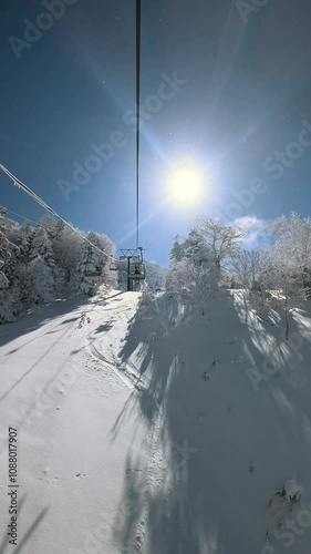 Vertical video of a ski chairlift ascending a mountain