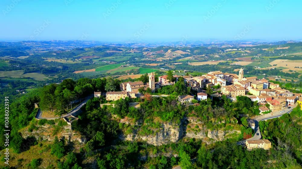 Impressive aerial pedestal down shot of Monte San Martino, camera descending to include the perched town's deeper roots with a car cruising the lower road, churches, belltowers and buildings, greenery Impressive aerial pedestal down shot of Monte San Martino, camera descending to include the perched town's deeper roots with a car cruising the lower road, churches, belltowers and buildings, greenery