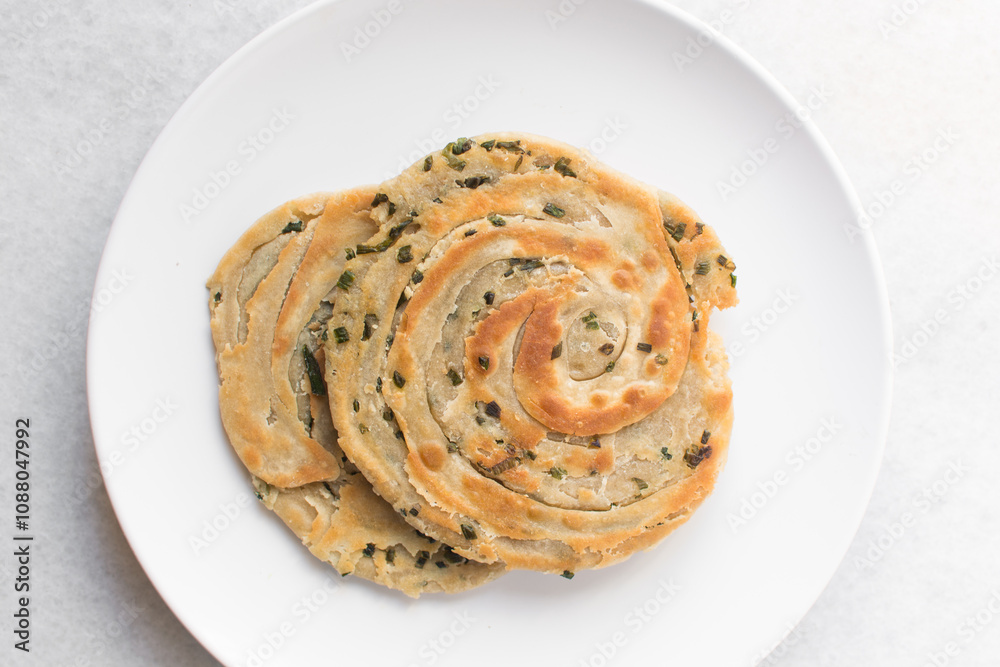 Overhead view of chinese scallion pancakes on a white plate, top view of golden-brown homemade scallion pancakes, process of making cong you bing Overhead view of chinese scallion pancakes on a white plate, top view of golden-brown homemade scallion pancakes, process of making cong you bing