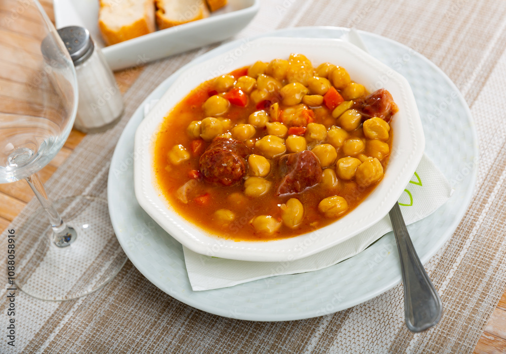 Thick and satisfying stew soup made from pork, beef, poultry, sausages with vegetables and chickpeas Thick and satisfying stew soup made from pork, beef, poultry, sausages with vegetables and chickpeas