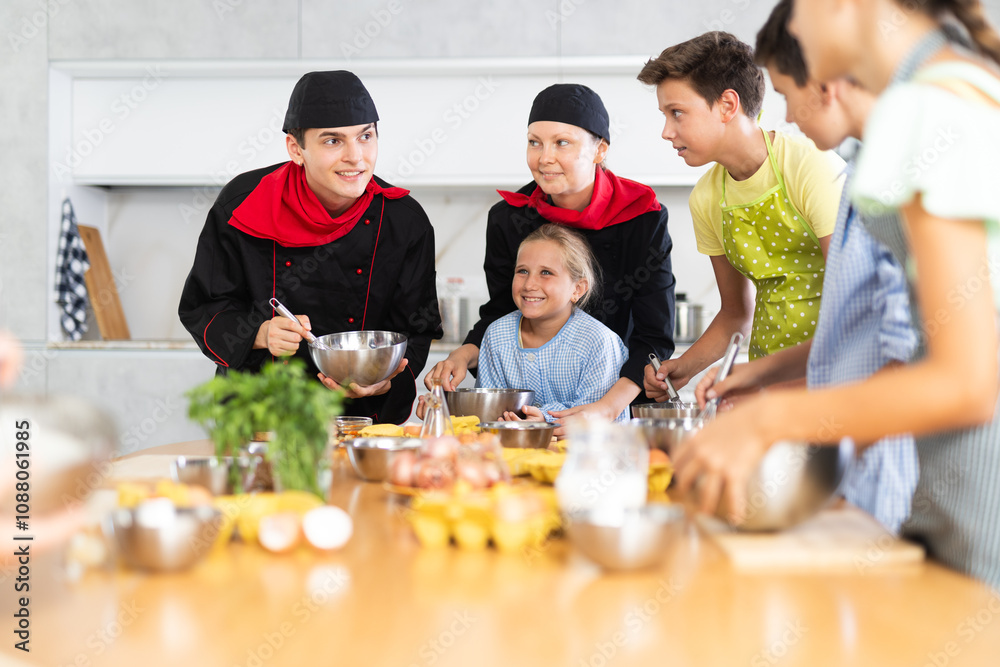 ..Young guy and adult woman chef at master class teaches group of children how to cook food ..Young guy and adult woman chef at master class teaches group of children how to cook food