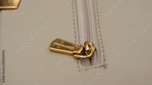 Close-up of a Gold Zipper Pull on a Beige Leather Bag
