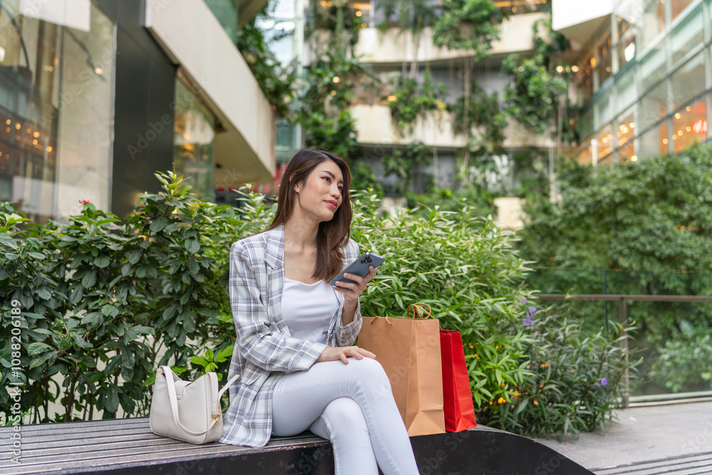 Asian Woman with Shopping Bags Sitting Using Phone While Taking A Break from Shopping Asian Woman with Shopping Bags Sitting Using Phone While Taking A Break from Shopping