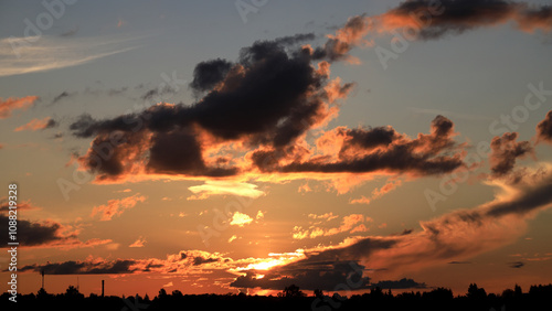 Real majestic sunset or sunrise sundown sky background with gentle colorful clouds without birds over forest. photo