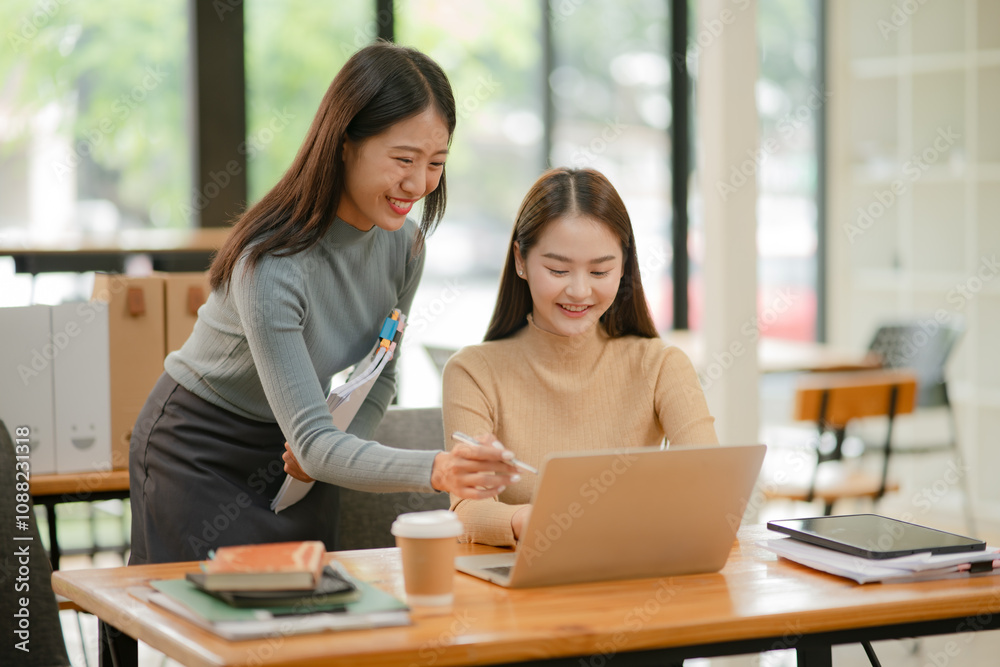 Two Asian businesswomen working with documents in an office. Two Asian businesswomen working with documents in an office.