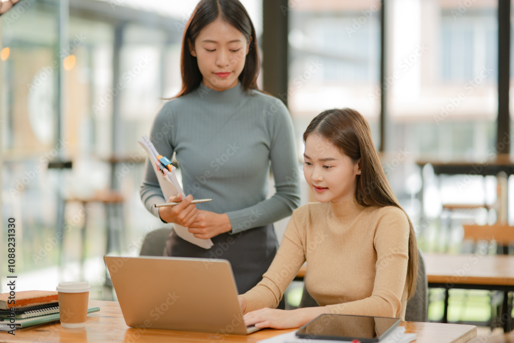 Two Asian businesswomen working with documents in an office. Two Asian businesswomen working with documents in an office.