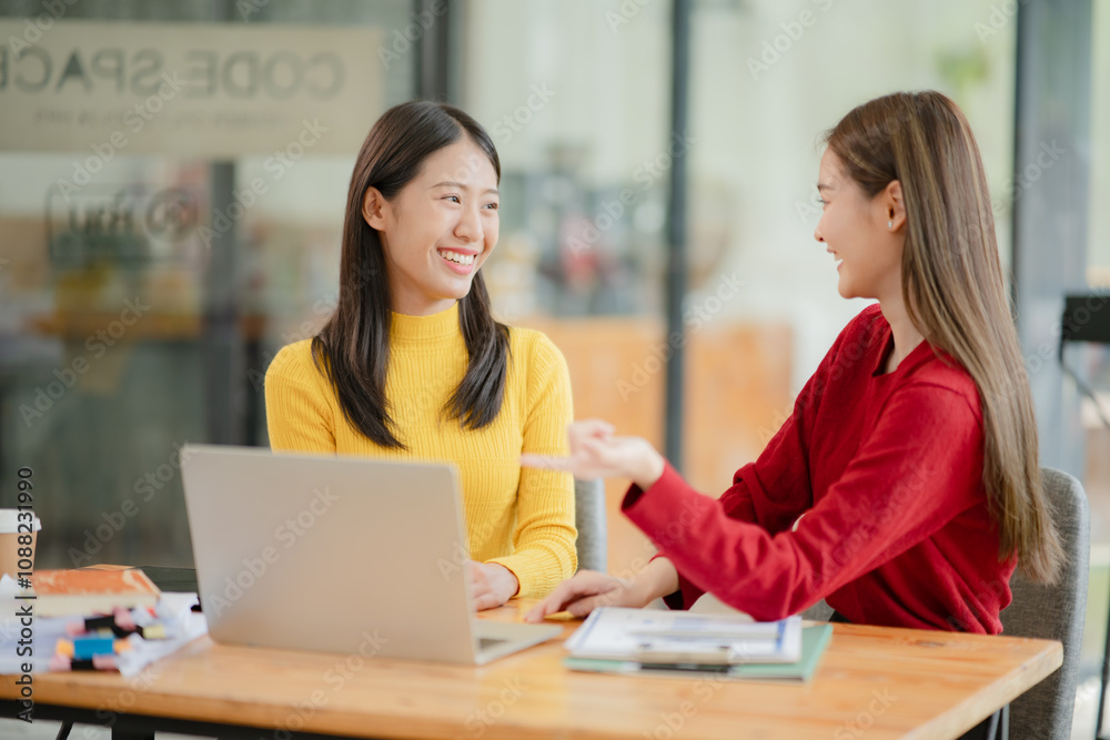Two Asian businesswomen working with documents in an office. Two Asian businesswomen working with documents in an office.