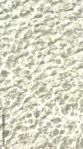 Sunlit ocean water rippling over sandy seabed, creating intricate light reflections and wave patterns in shallow water along a Florida shore.