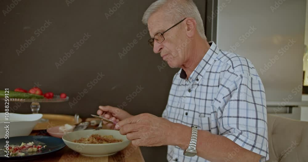 An older man sitting at his kitchen table enjoying a healthy lunch. He is eating alone and seems content. Perfect for lifestyle, nutrition, and health concepts. An older man sitting at his kitchen table enjoying a healthy lunch. He is eating alone and seems content. Perfect for lifestyle, nutrition, and health concepts.