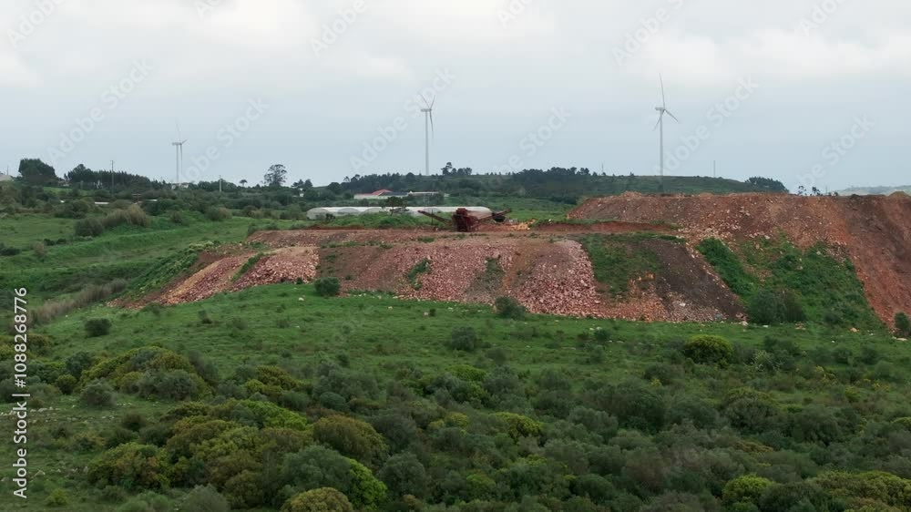 Drone shot over hill with windmills and heavy machine Drone shot over hill with windmills and heavy machine
