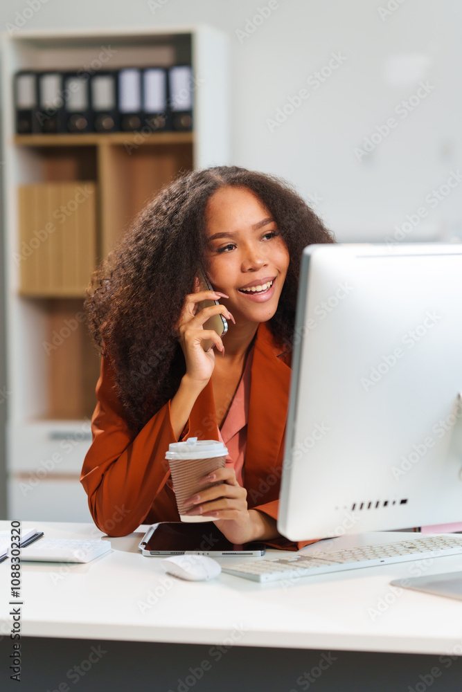 A cheerful African-American businesswoman works with a laptop in an office. She smiles confidently as she analyzes data, plans strategies, and manages her business operations A cheerful African-American businesswoman works with a laptop in an office. She smiles confidently as she analyzes data, plans strategies, and manages her business operations