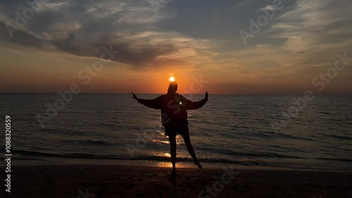 The silhouette of a girl dancing on the sand against the background of sunset and the horizon of the sea. 4k video. High quality 4k footage.