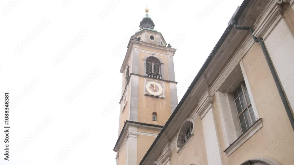 Low-angle view of classic architecture historic church clock tower in southern European town. Low-angle view of classic architecture historic church clock tower in southern European town.
